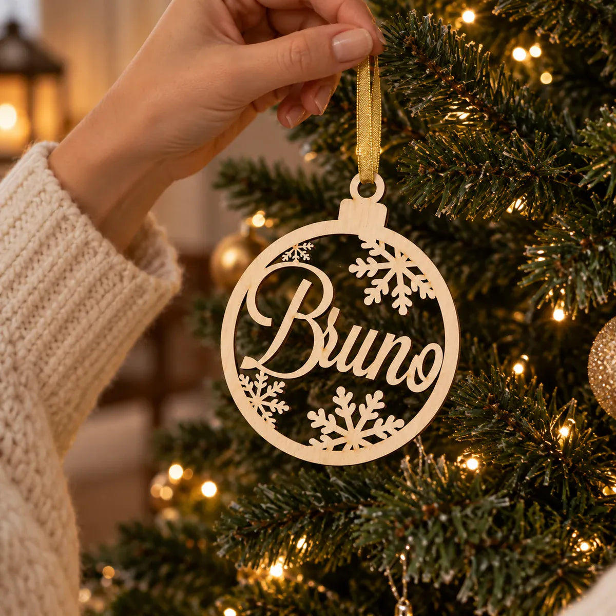 Wood name bauble being hung on a Christmas tree