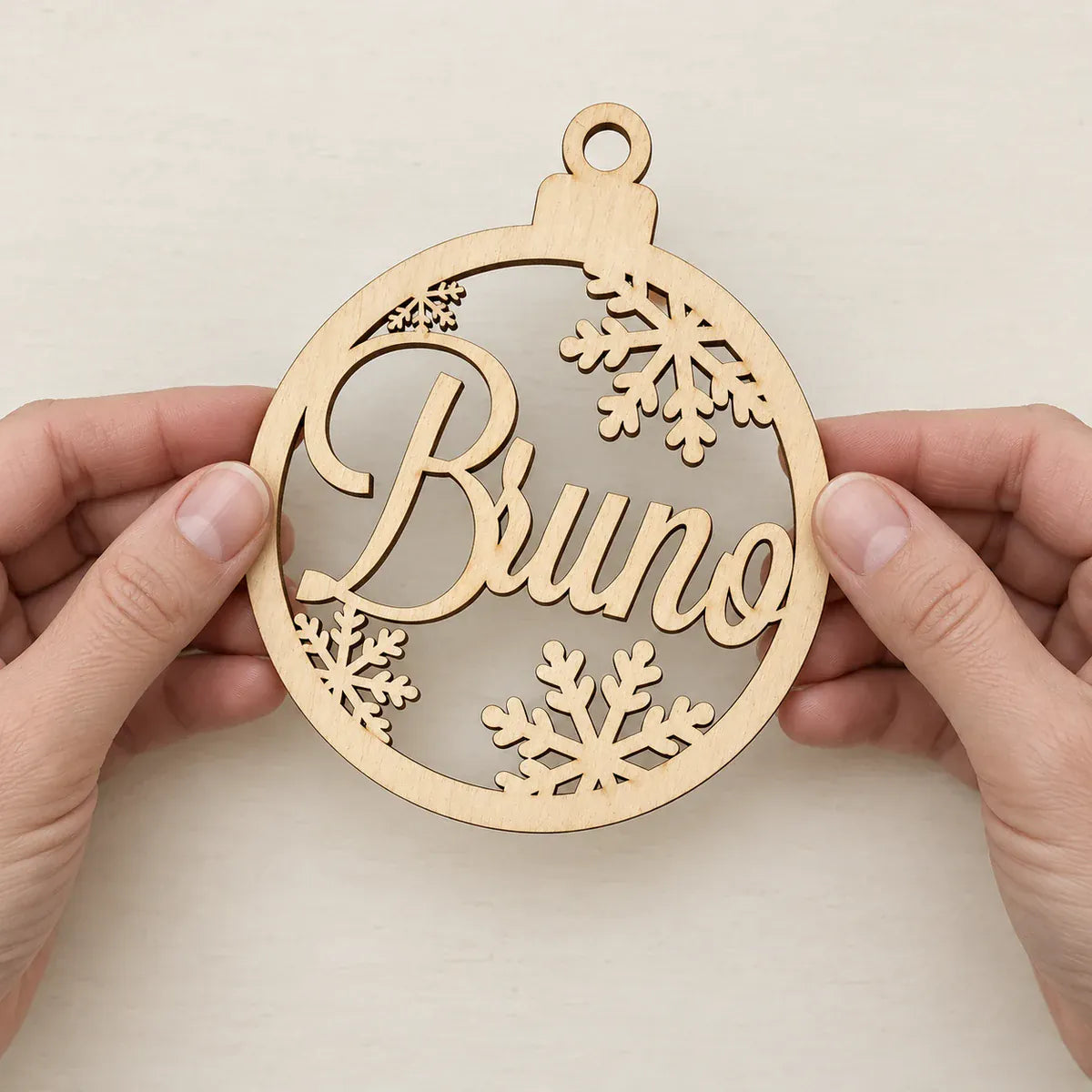 Wood name bauble held in two hands for a sense of scale